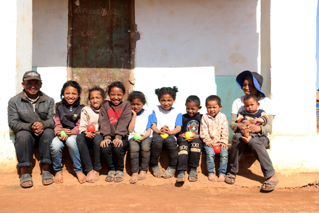 Les enfants de Mme Sylvie et de Mr Victor assis devant leur maison